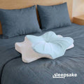 Sleepsake butterfly pillow on a bed with gray bedding and pillows.